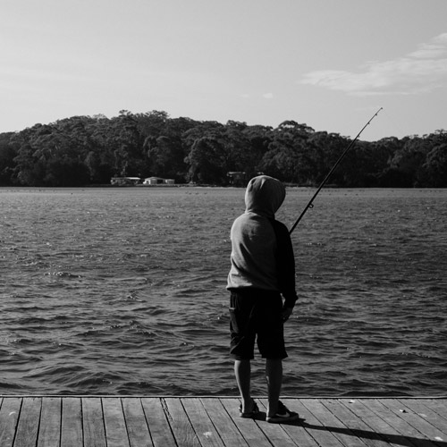 young boy fishing on jetty